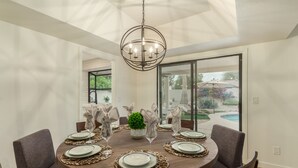 A dining area with a round table set for six, surrounded by six grey upholstered chairs. - Single-Level 3BR Scottsdale Home | Pool Table, Fire Pit (Scottsdale)