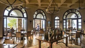 A spacious dining area with high arched windows, wooden tables, and chairs.