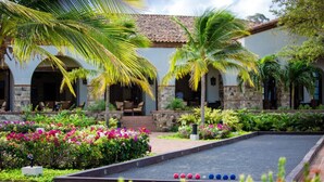 A courtyard with a shuffleboard table, palm trees, and a building with arches.