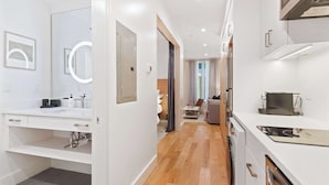 A modern, well-lit kitchen with white cabinetry, a built-in oven, and a microwave. - The Iris, Signature Suite (Charleston)