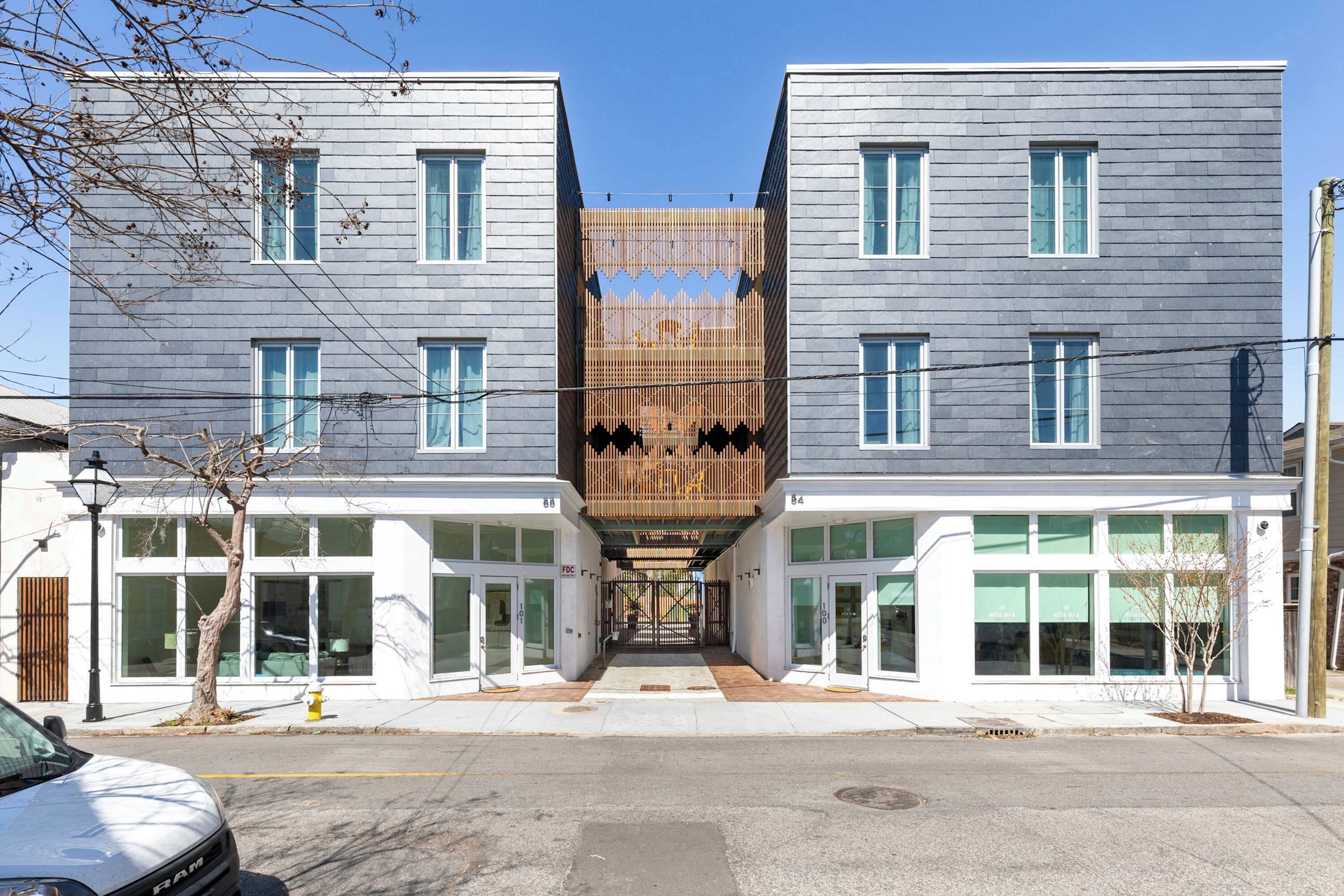 A modern building with a central wooden facade, large windows, and a clear sky.