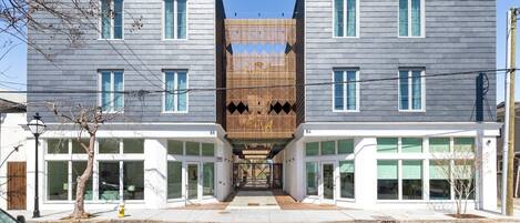A modern building with a central wooden facade, large windows, and a clear sky.