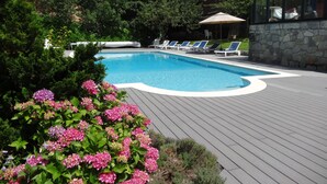 Una piscina con sillones de descanso y un muro de piedra.