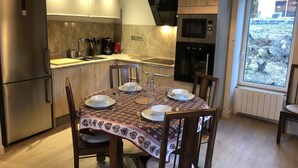 Una cocina moderna con comedor, equipada con electrodomésticos de acero inoxidable, un ventanal y vistas al exterior.
