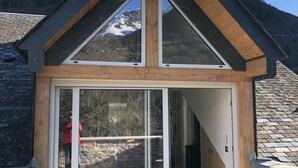 Un chalé moderno con un amplio ventanal corredero, fachada de madera y tejado inclinado.