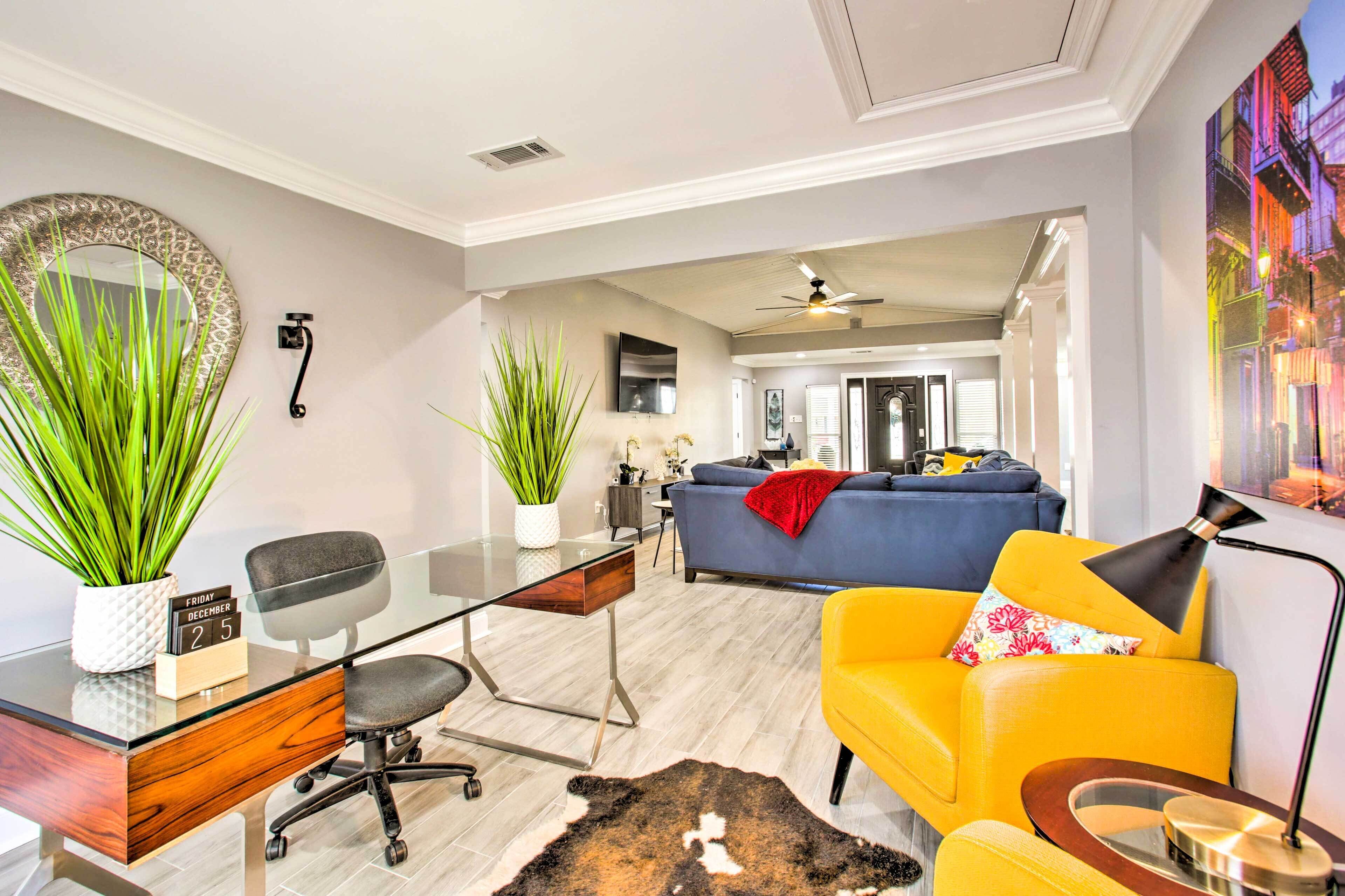 A modern living room with a glass desk, a sofa, and a yellow armchair.