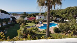 A pool surrounded by greenery, a clear sky, and a view of the sea. - Holiday Home "Casa Los Pinos" with Sea View, Shared Pool, Balcony, A/C & Wi-Fi (Sitio de Calahonda)