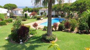 A residential area with a swimming pool, palm trees, and well-maintained lawns. - Holiday Home "Casa Los Pinos" with Sea View, Shared Pool, Balcony, A/C & Wi-Fi (Sitio de Calahonda)
