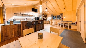 Interior em madeira com cozinha, sala de jantar e espaço para sentar.