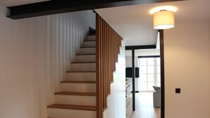 A modern staircase with wooden steps and a black handrail, leading to a bright room with a large window. - Reet Kate|3SZ|Sauna|Garding in St. Peter-Ording (Garding, Kirchspiel)