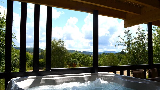 Un bain à remous avec une terrasse en bois et une vue sur un paysage montagneux.