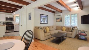 A modern living room with a sectional sofa, a dining table, and a kitchen in the background.
