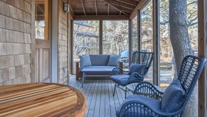 A wooden deck with a built-in bench and chairs, a table, and a view of a house and trees. - Private Location w/ Guest House! (Wellfleet)