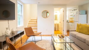 A modern living room with a sofa, two chairs, a coffee table, and a TV mounted on the wall.