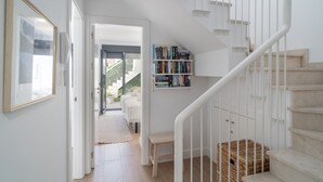 Un escalier avec une rampe blanche, une bibliothèque remplie de livres et un tableau encadré accroché au mur.