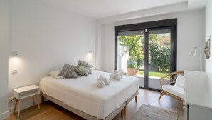 Une chambre avec un grand lit, une table de chevet, une chaise et une vue sur l’extérieur grâce à une porte coulissante.