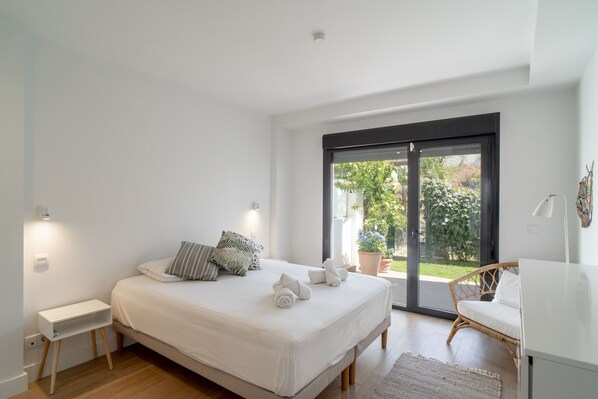 Une chambre avec un grand lit, une table de chevet, une chaise et une vue sur l’extérieur grâce à une porte coulissante.