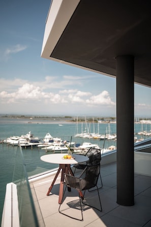 A balcony with a table and chairs, overlooking a marina with boats. - Laguna Faro Suites - Adults Only & Free Beach (Grado)