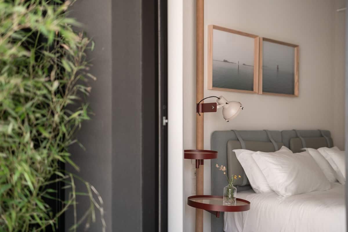 A modern bedroom with a bed, bedside tables, a lamp, and two framed pictures on the wall.
