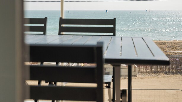 Un balcón con vista al mar, que incluye una mesa y sillas.