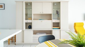 Una habitación moderna con un armario blanco, una mesa de comedor y una silla amarilla.