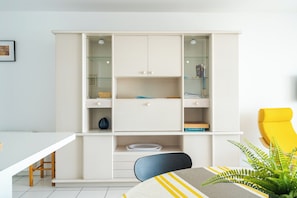 Une pièce moderne avec un meuble blanc, une table à manger et une chaise jaune.