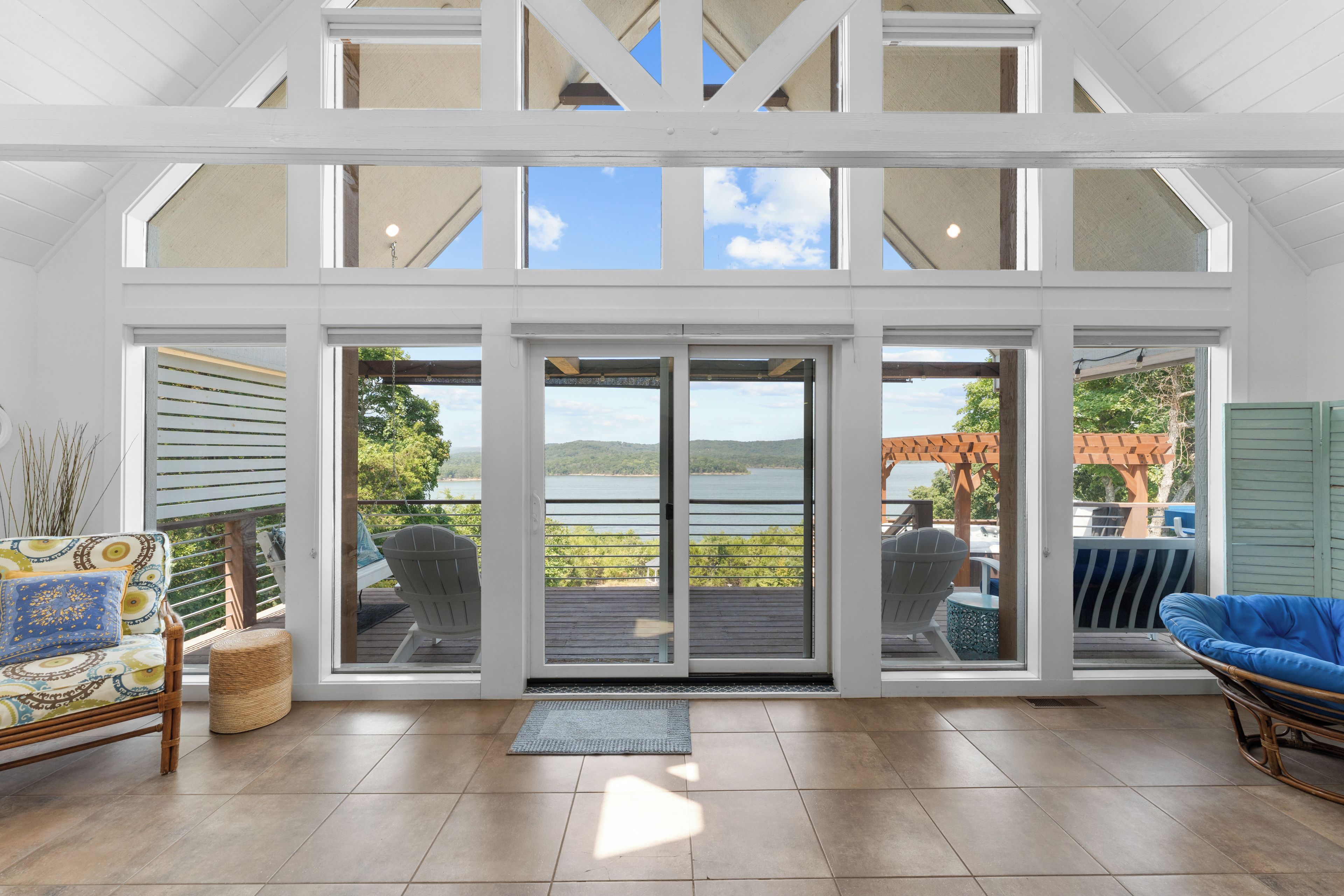 A spacious room with a large sliding glass door leading to a deck with a view of a lake.