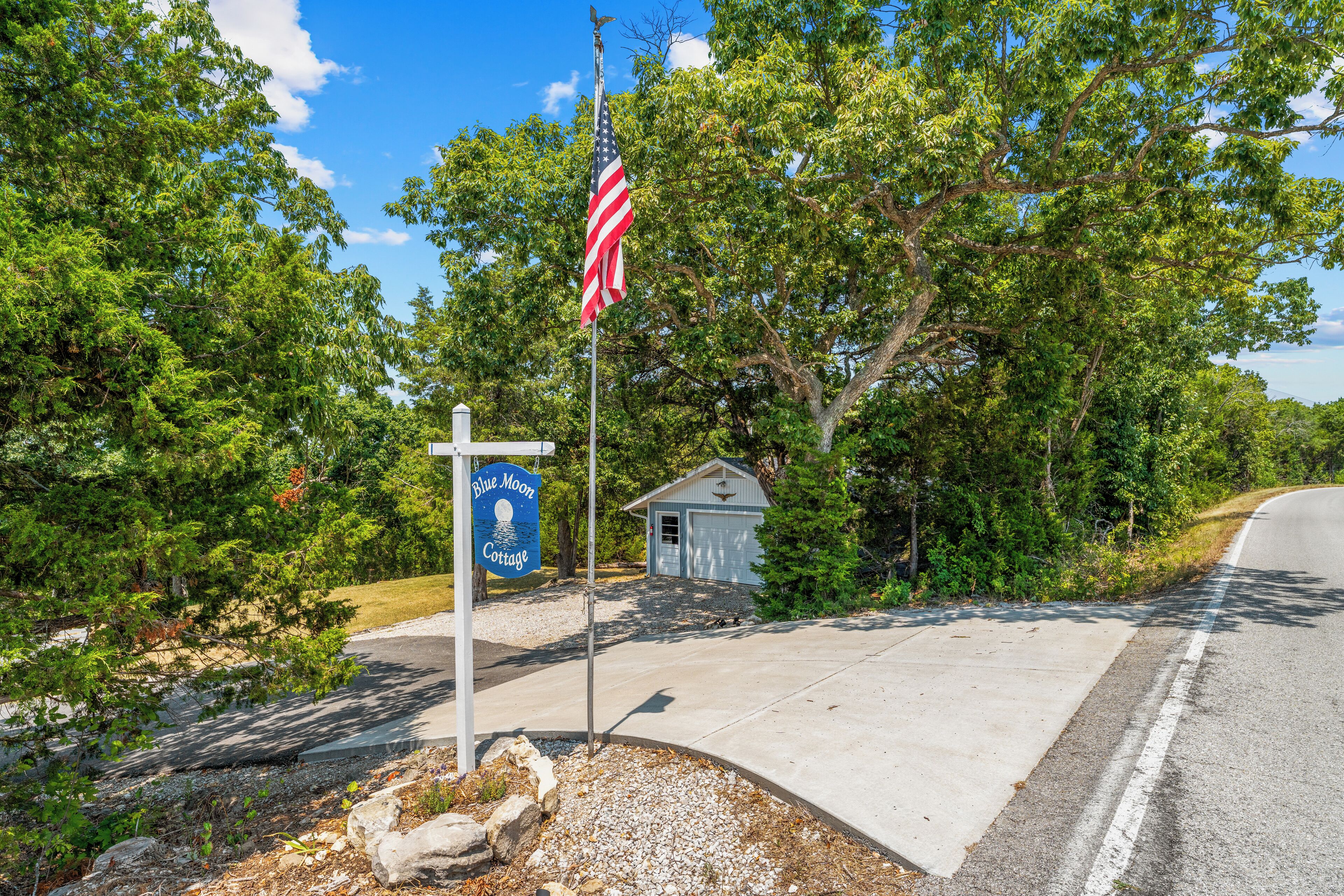 A sign for Blue Moon Cottage with a flagpole and a small building in the background.