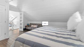 Ein Schlafzimmer mit einem großen Bett, einer Couch und einem Deckenventilator. Eine Tür führt zu einem Balkon.