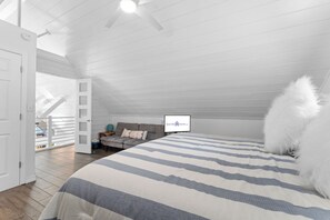 A bedroom with a large bed, a sofa, and a ceiling fan. There is a door leading to a balcony. - Enchanting Cottage with Sweeping Lake Views, Golden Sunsets, Hot Tub, Nature Trail & Dog-Friendly (Blue Eye)