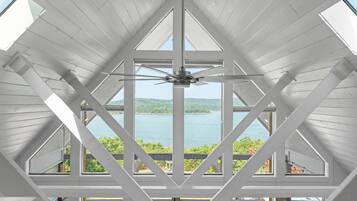 A room with a sloped ceiling and large windows offering a view of a lake and greenery.