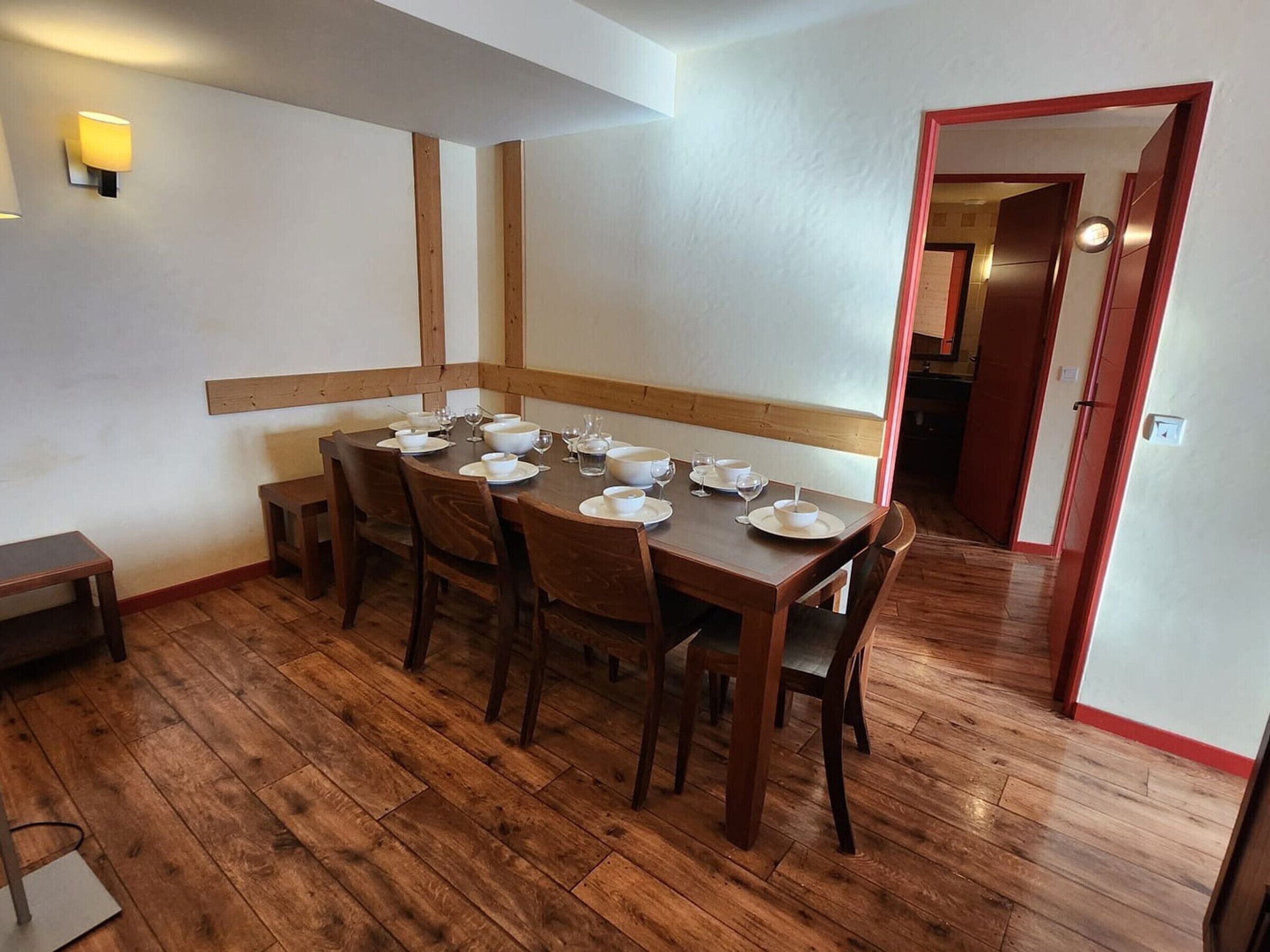 Un'area pranzo con un tavolo in legno apparecchiato per quattro persone, circondato da sedie.