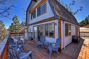 A two-story house with a deck, outdoor seating, and large windows.