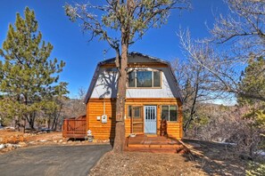 A wooden cabin with a front porch, a large window, and a door.