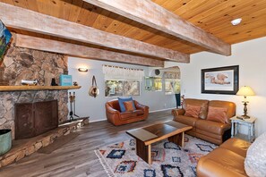 A cozy living room with a stone fireplace, leather sofas, a coffee table, and a patterned rug.
