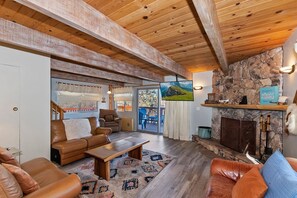 A spacious living room with a fireplace, leather sofas, a coffee table, and a stone wall.