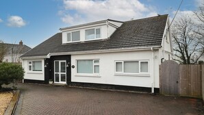 A two-story house with a tiled roof, a front door, and a small garden area. - Ocean Waves - Ground Floor Apartment Pet Friendly Enclosed Garden (Saundersfoot)