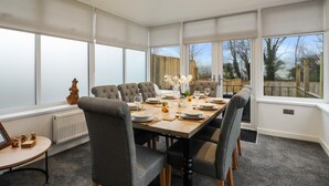 A dining room with a large table set for six, surrounded by grey upholstered chairs. - Plas Gwyn - Walk to Beach Parking Enclosed Garden (Saundersfoot)