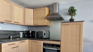 A modern kitchen with wooden cabinets, stainless steel appliances, and a built-in oven. - Ski-in Duplex, 3 Rooms, 6 pers., Arc 1800 (Les Arcs 1800)