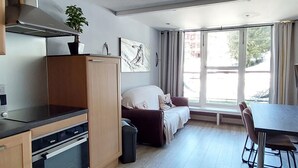 A compact kitchen with modern appliances, a dining area with a table and chairs, a sofa, and a large window with a view of the street. - Ski-in Duplex, 3 Rooms, 6 pers., Arc 1800 (Les Arcs 1800)