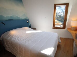 Un dormitorio con una cama, un ventanal y un mural en la pared.