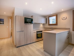 Una cocina compacta con horno empotrado, refrigerador y microondas.