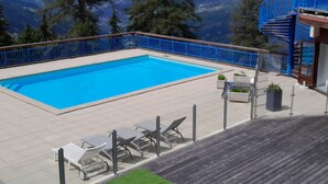 A swimming pool with a blue railing, surrounded by a wooden deck and a view of mountains. - 2-room apartment for 4 people in Arc 1800, balcony and equipped kitchen (Les Arcs 1800)
