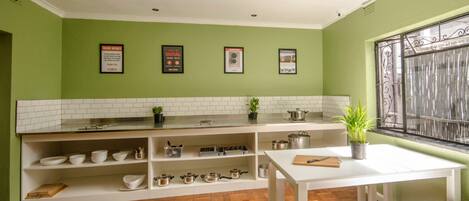A kitchen with white cabinets, a wooden floor, and a window with a metal grill.