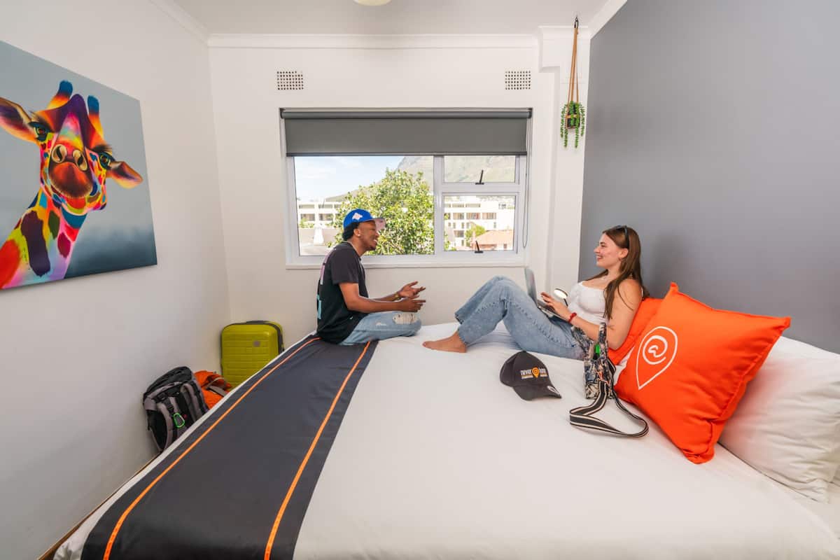 Ein Zimmer mit einem Bett, einem Fenster, einem Gemälde und einem Koffer.