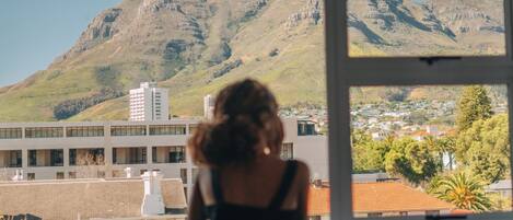 A person looking out of a window at a mountain and a town.