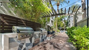 Un área de cocina al aire libre con una parrilla, una mesa de comedor y sillas.