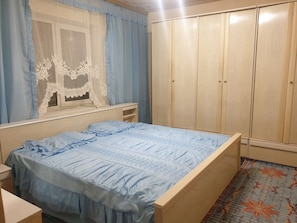 Une chambre à coucher avec un lit, une armoire et une fenêtre avec des rideaux.