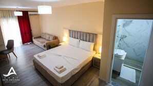 A hotel room with a bed, a sofa, a desk, and a bathroom. - New Akileda Hotel (Golem)
