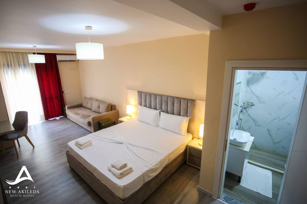 Una habitación de hotel con cama, sofá, escritorio y baño.